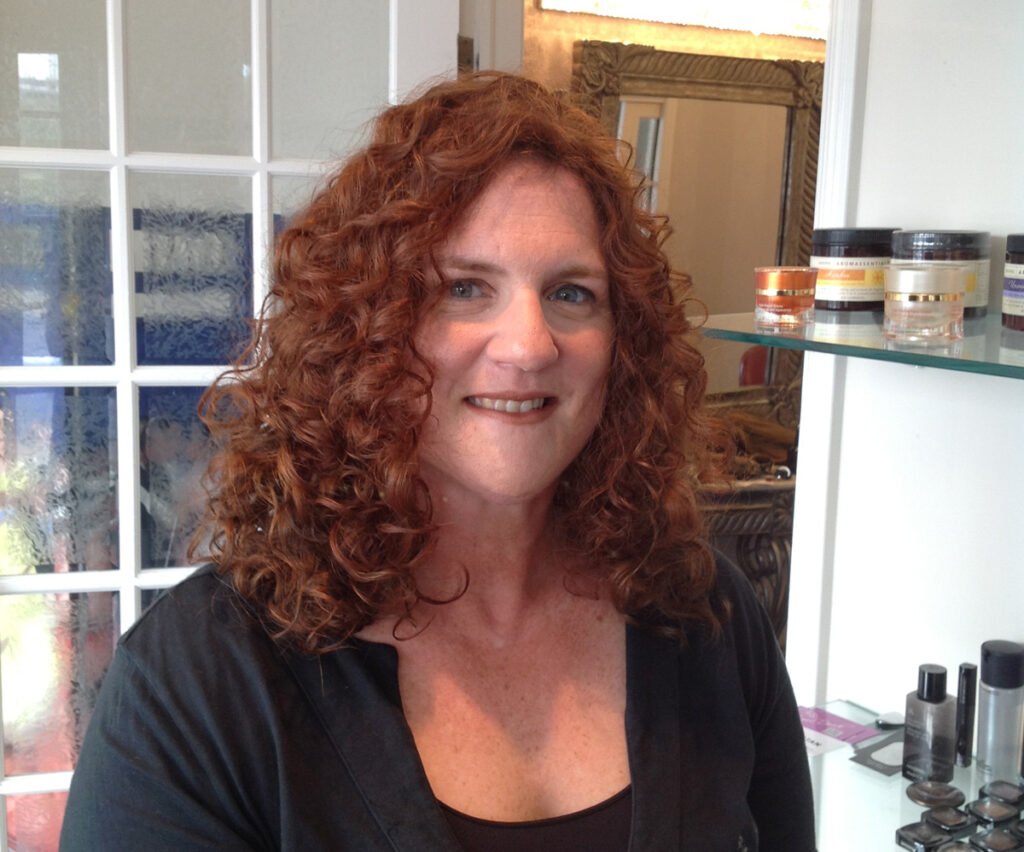 Woman wearing curly hair wig and sitting in Paula's Miami wig shop