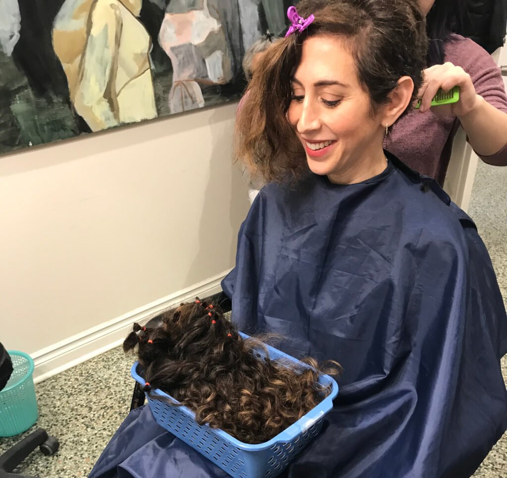 Woman in Toronto wig boutique workshop. Her hair is being cut to make into a human hair wig of her own.